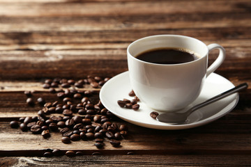 Cup of coffee with coffee beans on brown wooden background