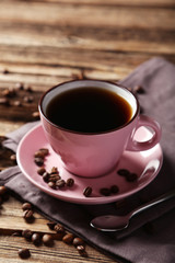 Cup of coffee with coffee beans on brown wooden background