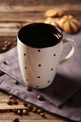 Cup of coffee with coffee beans on brown wooden background