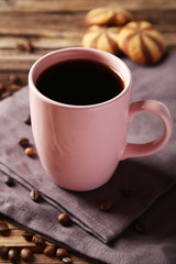 Cup of coffee with coffee beans on brown wooden background