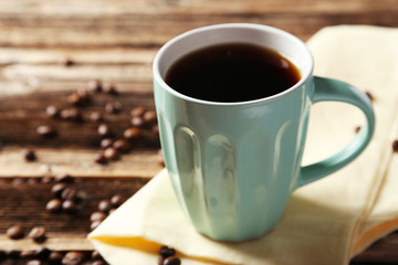 Cup of coffee with coffee beans on brown wooden background