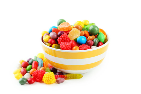 Colorful candies in bowl on white background