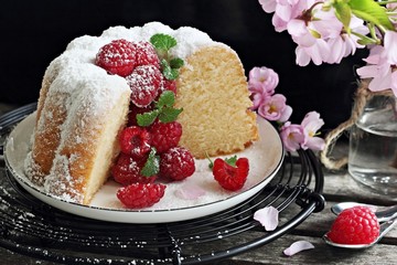 Vanilla cake with fresh raspberries on a rustic dark background 