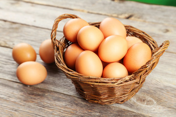 Chicken eggs in basket on grey wooden background