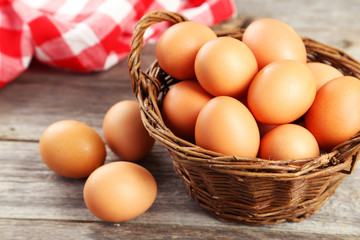 Chicken eggs in basket on grey wooden background