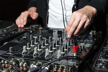 DJ at nightclub party mixes track on sound mixer
