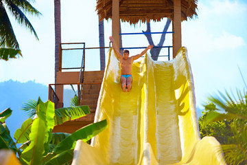 excited man having fun on water slide in tropical aqua park