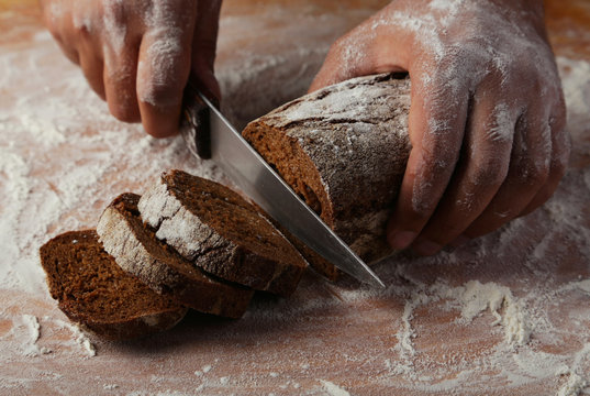 Male Hands Slicing Fresh Bread