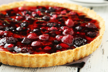 Fresh berry tart on white wooden background