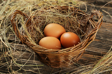 Eggs in basket on brown wooden background