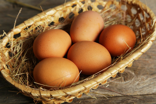 Eggs in basket on brown wooden background