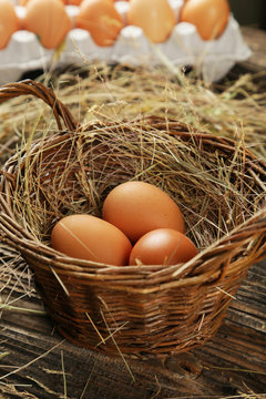 Eggs in basket on brown wooden background