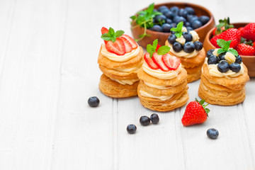 homemade puff pastry stuffed with cream and berries on white tab