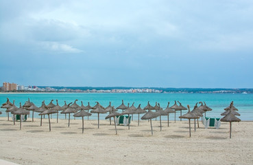 Fototapeta na wymiar Can Pastilla beach with sun parasols in spring. Mallorca.