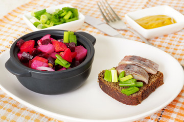 Винегрет, зеленый лук и сэндвич с селедкой.