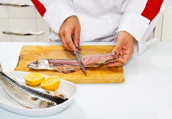 woman chef preparing fillet of mackerel