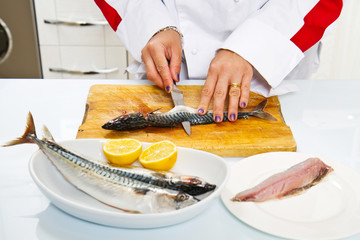 woman chef preparing fillet of mackerel