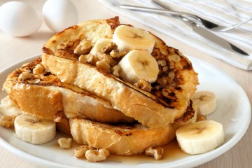 French toast with bananas, walnuts and dripping maple syrup - obrazy, fototapety, plakaty