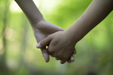 The hands of children holding hands in the forest