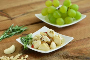 Antipasti - Knoblauch, Rosmarin, Trauben auf Holztisch