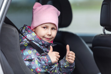 Child in booster chair fasten with car seatbelt, thumbs up