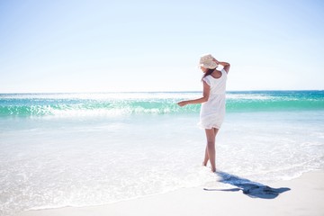 Pretty brunette wearing straw hat and walking in the water