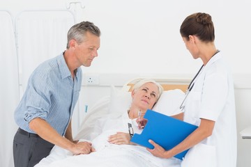 Doctor explaining report to female patient and husband