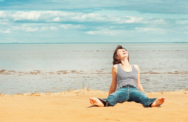 Fototapeta na wymiar Laughing woman sitting on the beach