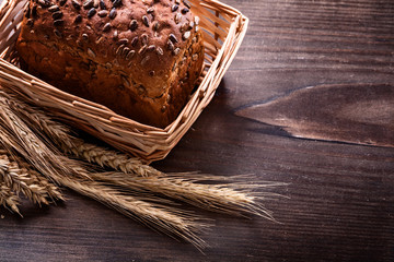 Crusty bread with seeds in wicker basket wheat ears on vintage p