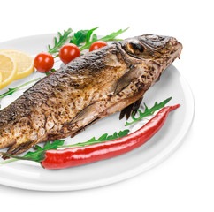Grilled carp with vegetables on plate.