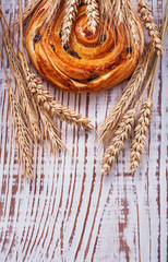 Raisin bun wheat ears on vintage wooden board food and drink con