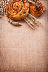 Ripe wheat ears rich raisin baked rolls on oaken wooden board fo