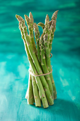 bunch of fresh asparagus on turquoise background
