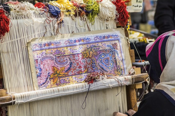 Turkish carpet weaver weaves on a loom on the street