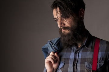 a young man with a beard holding a denim jacket  