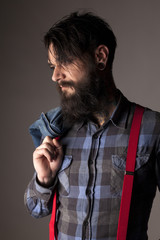 a young man with a beard holding a denim jacket  