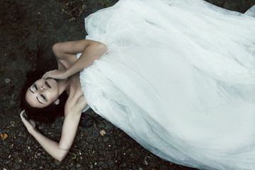Woman lying on the shore in white dress, dark mystery scene