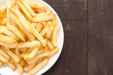 French fries on white dish on wooden background