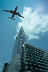 Fototapeta na wymiar Airplane in the sky with modern buildings