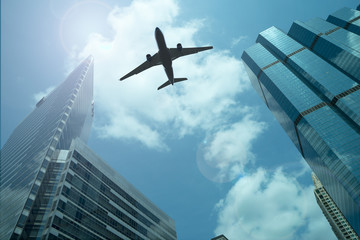 Fototapeta na wymiar Airplane in the sky with modern buildings