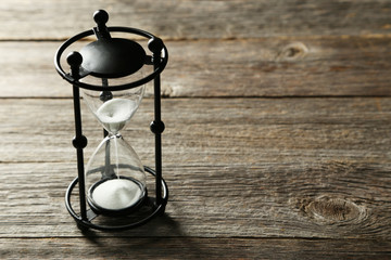 Black hourglass on grey wooden background