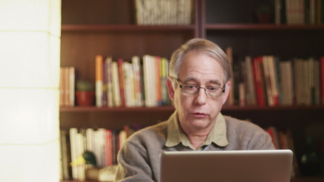 A older man talking over a video chat using his laptop.