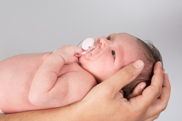 New born baby is held by his father isolated on grey