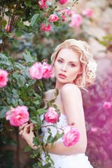 Attractive young bride posing near roses garden