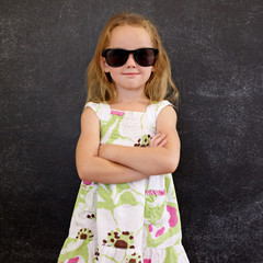 Cute little girl in shades against a black wall
