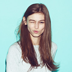 Emotional pretty young hipster girl make funny face on blue