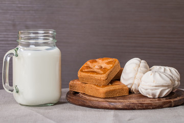 Fresh milk in glass and sweet cookies with zephyr