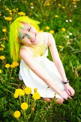 Fototapeta na wymiar Beautiful young woman with yellow hair in grass with dandelion