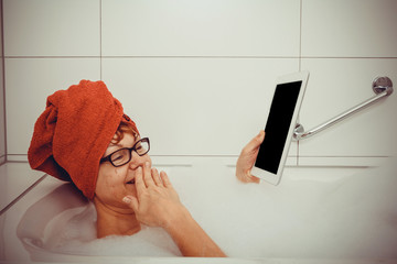 Confused woman in bathtub with tablet computers, space for text