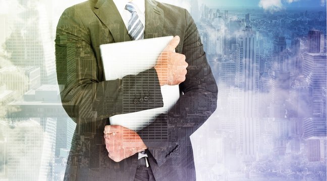 Composite image of businessman holding his laptop tightly